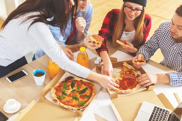 Equipo comiendo pizza en el lugar de trabajo