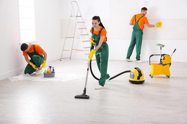 Equipo de conserjes profesionales que limpian la sala después de la renovación