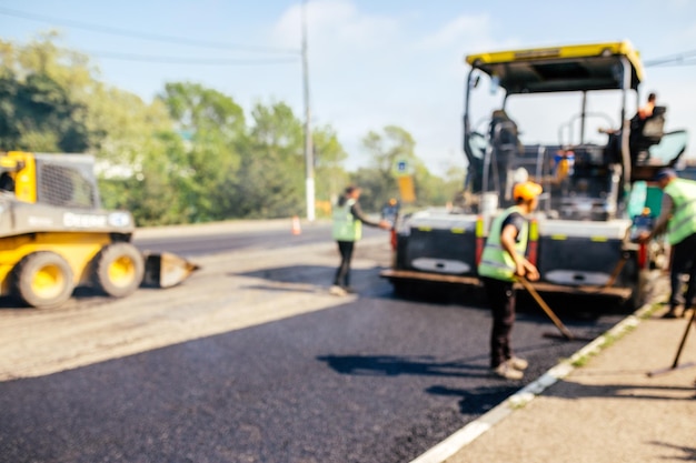 El equipo de construcción de carreteras usó palas para esparcir más asfalto sobre la parte superior del nuevo pavimento