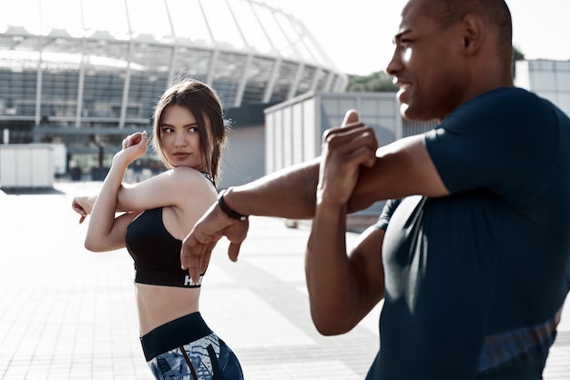 Equipo de corredores saludables de deportes urbanos calentando y estirando en el parque de la ciudad antes del entrenamiento matutino