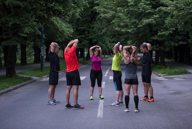 equipo de corredores sanos calentando y estirando en el parque de la ciudad antes del entrenamiento de la mañana