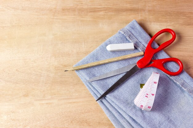 Equipo para cortar telas de jeans sobre fondo de madera marrón