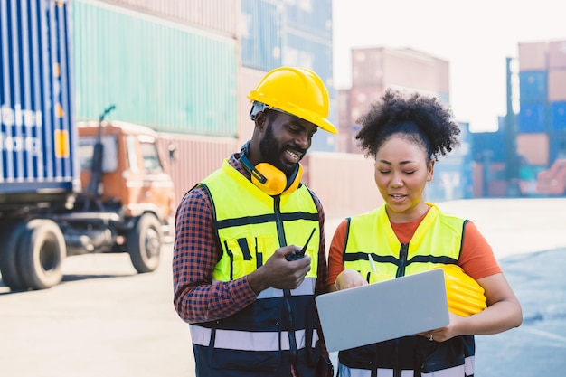 Equipo de coworking de pareja de trabajadores negros africanos juntos en el patio de contenedores de carga de la industria de transporte de carga portuaria