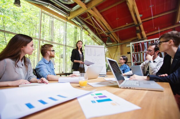 Equipo creativo. Diseñador gráfico femenino que tiene discusión con compañeros de trabajo en la oficina.