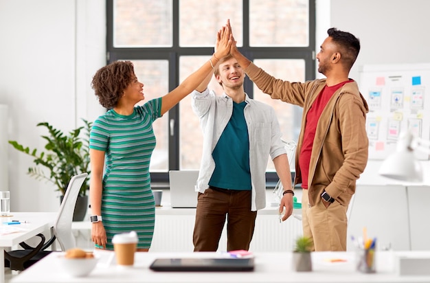 Equipo creativo feliz dando un "high five" en la oficina