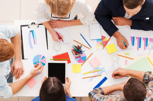 Equipo creativo en el trabajo. Vista superior de la gente de negocios en ropa casual elegante trabajando juntos mientras están sentados en la mesa