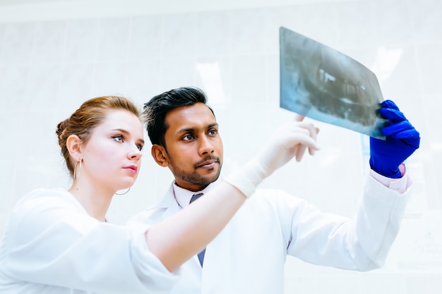 Equipo dental multirracial que controla la radiografía de los dientes del paciente. Concepto de clínica dental.