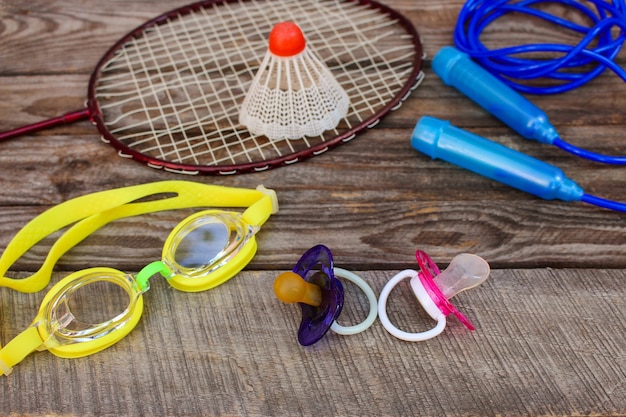 Equipo deportivo: el birdie está en la raqueta, la comba, las gafas de natación y las zapatillas de deporte sobre fondo de madera