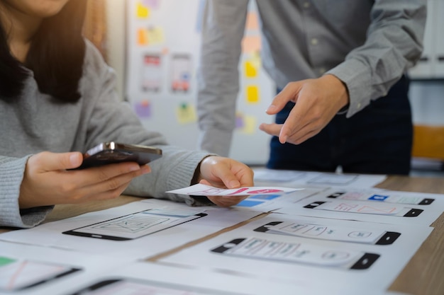 El equipo de desarrolladores de la agencia de desarrollo digital creativo hace una lluvia de ideas sobre su proyecto con un teléfono inteligente portátil y una tableta digital