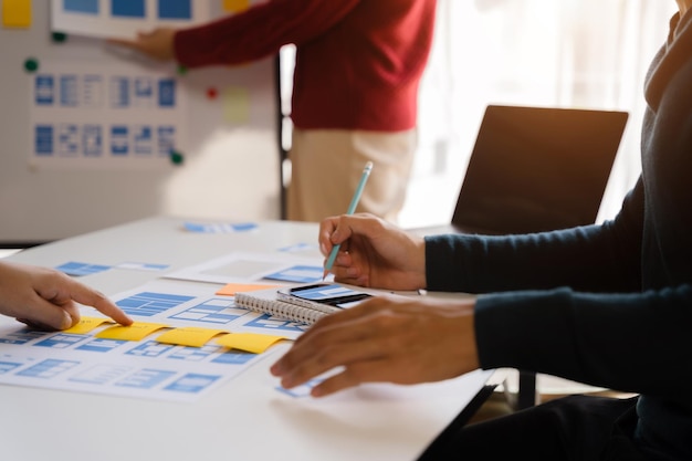 Foto el equipo de desarrolladores hace una lluvia de ideas sobre su proyecto con un teléfono inteligente portátil y una tableta digital