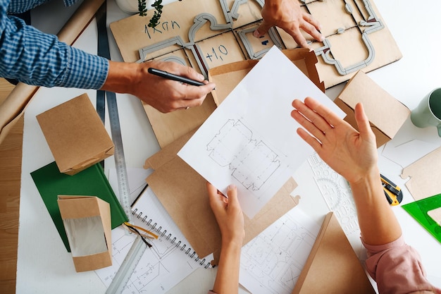 Equipo de diseñadores de cajas trabajan en el escritorio Manos de hombre y mujer en el trabajo