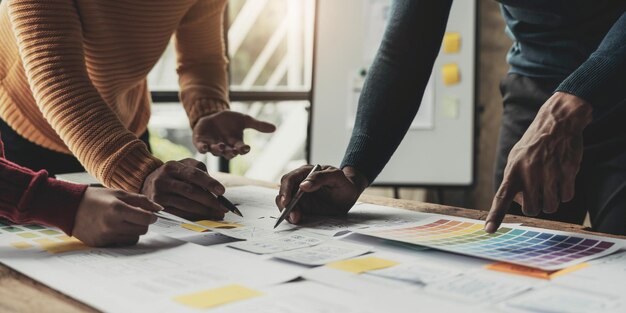 Equipo de diseñadores creativos de UIX diseñando el diseño de wireframe para una aplicación de teléfono inteligente móvil receptiva en la oficina