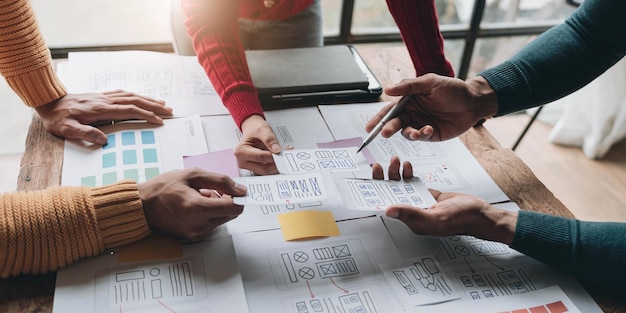 Equipo de diseñadores creativos de UIX diseñando el diseño de wireframe para una aplicación de teléfono inteligente móvil receptiva en la oficina