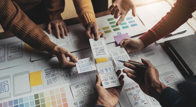 Equipo de diseñadores creativos de UIX diseñando el diseño de wireframe para una aplicación de teléfono inteligente móvil receptiva en la oficina