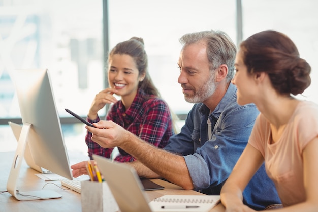 Equipo de diseñadores gráficos discutiendo sobre la computadora en el escritorio