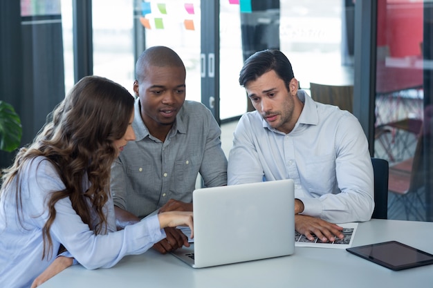 Equipo de diseñadores gráficos discutiendo sobre laptop