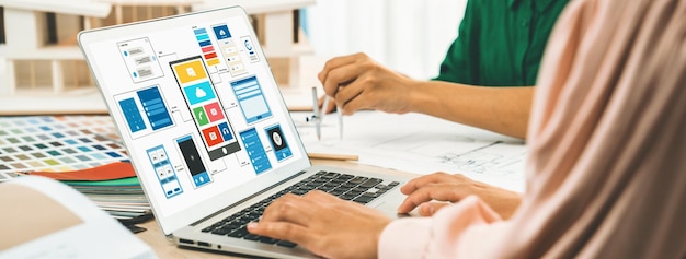 Foto el equipo de diseñadores presenta color mientras el portátil muestra diseños de interfaz de usuario y ux variados