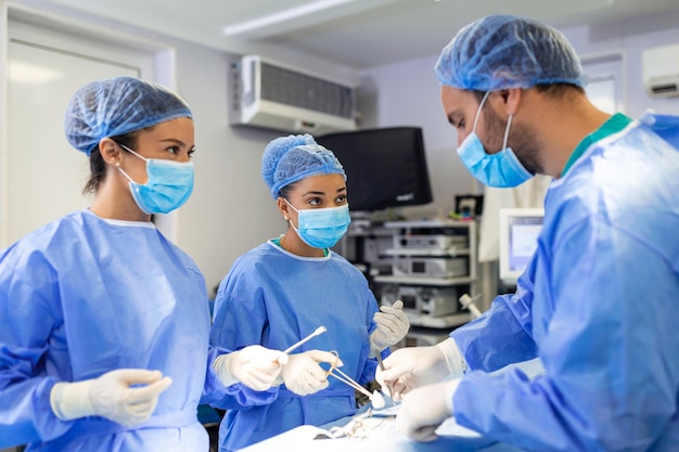 Equipo diverso de asistentes de cirujanos profesionales y enfermeras que realizan cirugía invasiva en un paciente en el quirófano del hospital Los cirujanos hablan y usan instrumentos Hospital moderno real