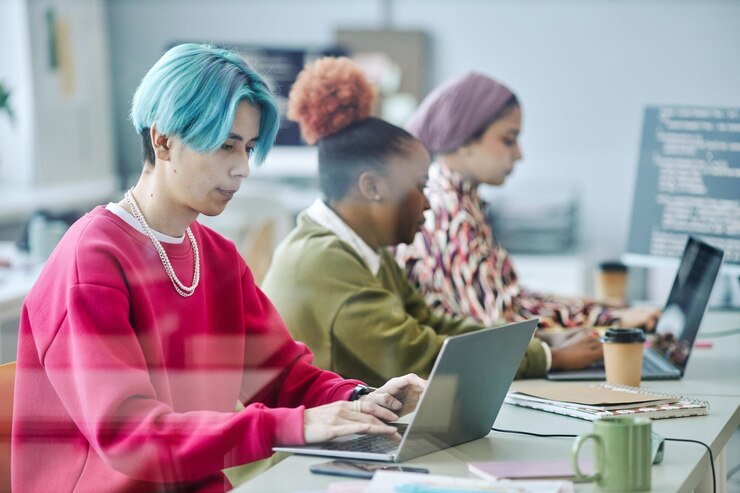 Foto equipo diverso de desarrolladores de software que usan computadoras detrás de un vidrio
