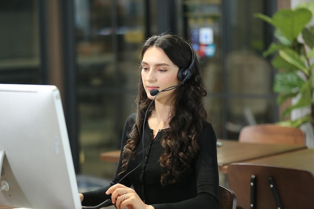 Equipo de diversos operadores de líneas directas con auriculares que brindan servicio a clientes en el centro de llamadas