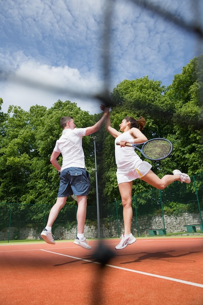 Foto equipo de dobles de tenis celebrando una victoria