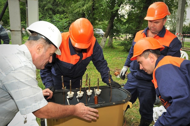 Un equipo de electricistas está haciendo reparaciones transformador de aceite de energía eléctrica trifásico