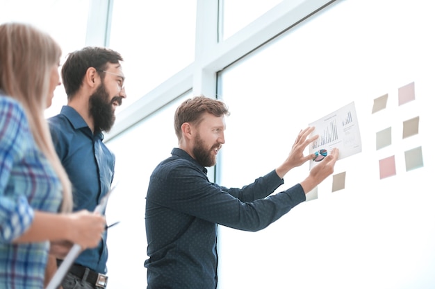 Equipo empresarial mirando el cuadro financiero en un tablero de vidrio