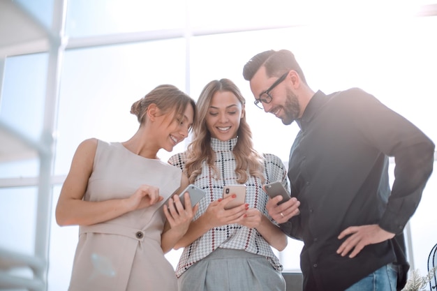 Foto equipo empresarial mirando las pantallas de sus smartphones