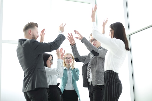 El equipo empresarial se regocija, de pie en la oficina.