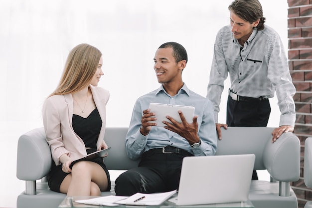 Equipo empresarial mediante tableta digital en el vestíbulo de la oficina