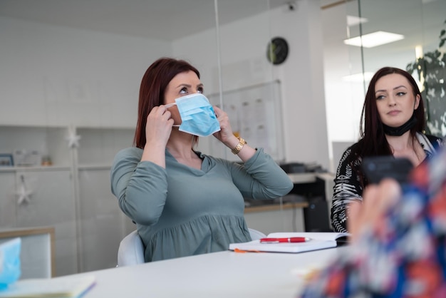 equipo de empresarios multiétnicos que trabajan en oficinas modernas y luminosas con máscara médica protectora durante el brote de coronavirus nuevo concepto normal en los negocios