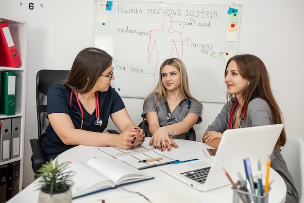 equipo con enfermeras sentadas en el escritorio y reuniéndose en el hospital