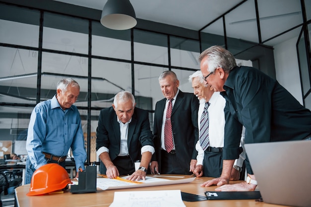 Equipo envejecido de arquitectos de negocios ancianos trabaja con plan en la oficina.