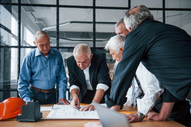 Equipo envejecido de arquitectos de negocios ancianos trabaja con plan en la oficina.