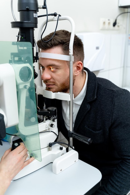 Equipo especial en clínica oftalmológica para corrección de visión. Equipos especiales correctivos tecnológicamente actualizados. Retrato de hombre en clínica.