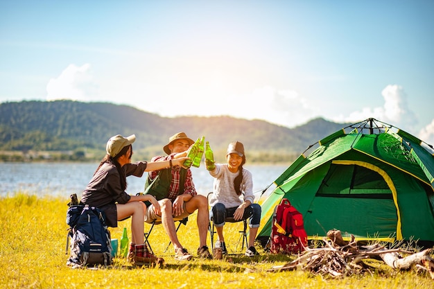 Equipo de excursionistas escaladores asiáticos están sentados y disfrutando de una bebida después de instalar una carpa al aire libre en la temporada de otoño del sendero del bosque. Senderismo, excursionista, equipo, bosque, camping, concepto de actividad.