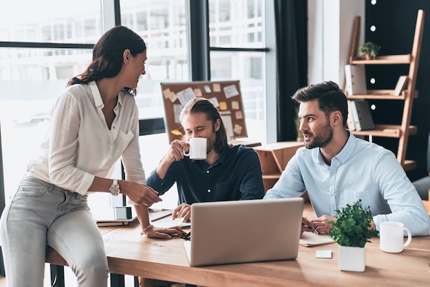 Equipo exitoso. Jóvenes colegas modernos en ropa casual elegante trabajando juntos y sonriendo