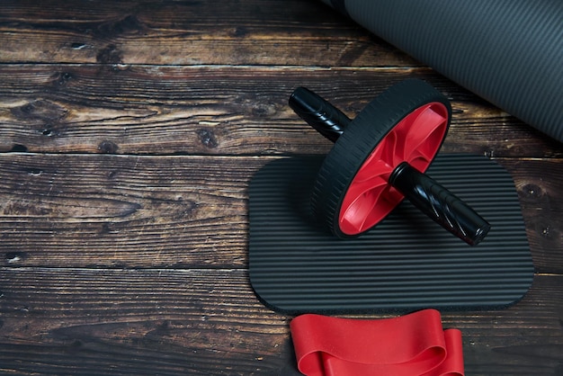 Equipo de fitness para gimnasio y hogar Banda de rueda de fitness Mat sobre fondo de madera oscura vista superior