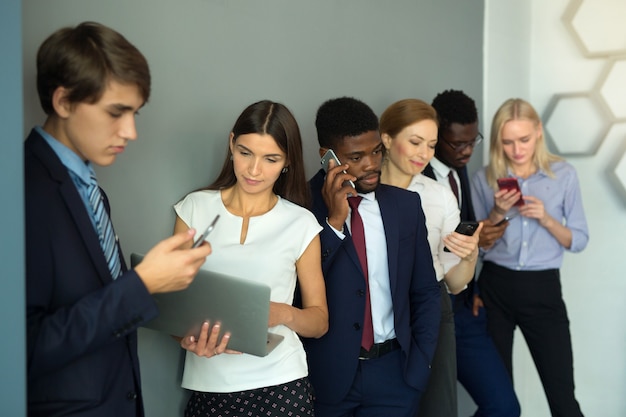 equipo de gente joven hermosa en la oficina con teléfonos móviles