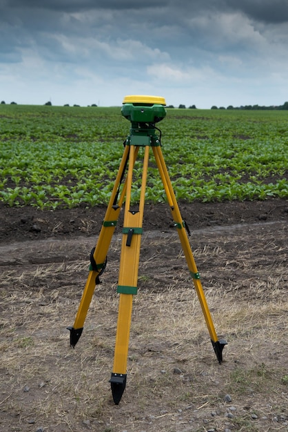 Foto equipo gps de trípode de nivelador montado en trípode en campo orgánico verde