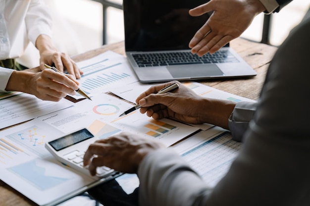 Equipo de hombres de negocios o analistas de datos financieros que trabajan juntos con tabletas y computadoras portátiles y gráficos de datos Plan para analizar proyectos en la oficina