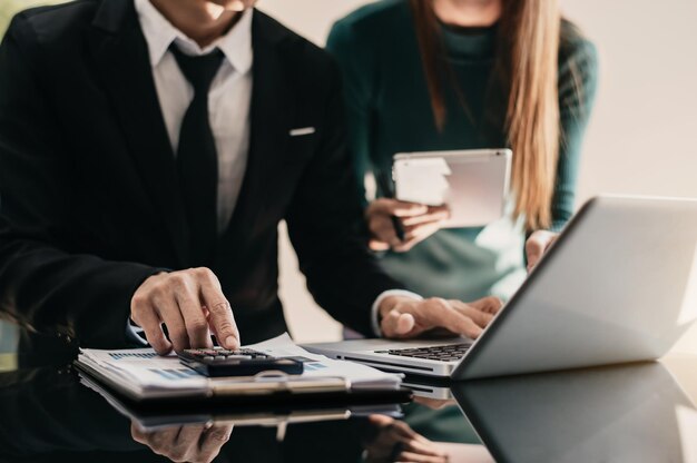 Equipo de hombres de negocios o analistas de datos financieros que trabajan juntos con tabletas portátiles y calculadoras y gráficos de datos Plan para analizar proyectos en la oficina