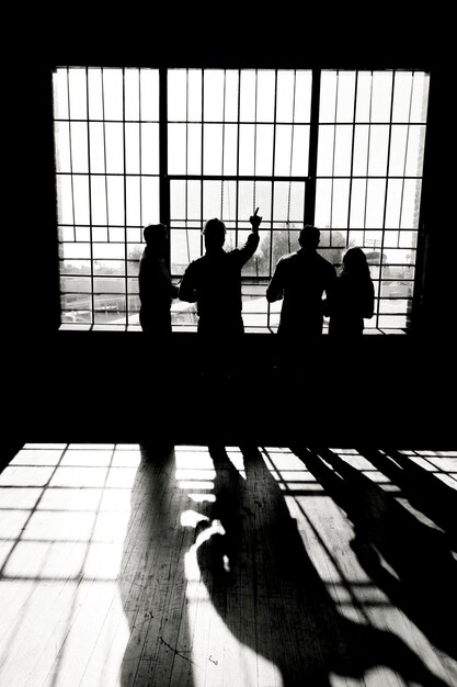 Equipo de ingeniería ecológico discutiendo por las ventanas de vidrio en escala de grises