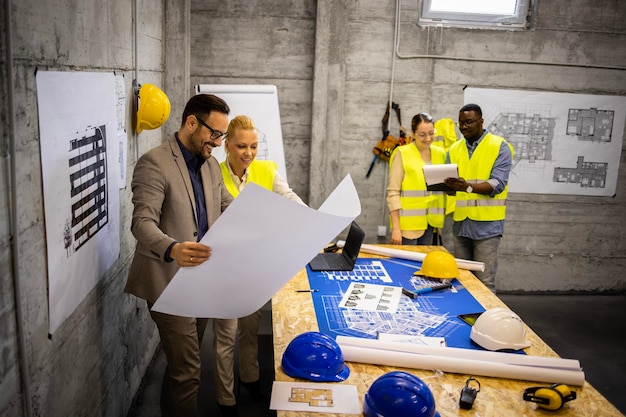 Foto equipo de ingenieros y arquitectos estructurales analizando planes y planos en el sitio de construcción