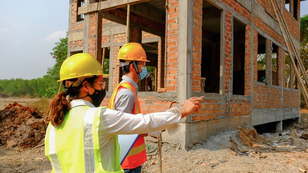 Foto el equipo de ingenieros contratistas se reúne con el proyecto de la industria del plan de seguridad laboral y verifica el diseño en el sitio de construcción.