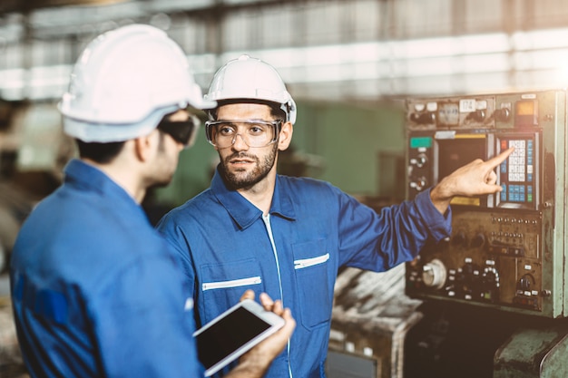 El equipo de ingenieros hablando juntos para discutir, enseñar y aprender ofrece educación técnica sobre el uso de la máquina en el lugar de trabajo de la fábrica.