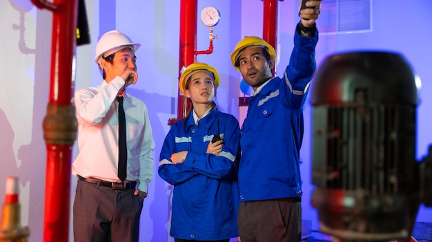 El equipo de ingenieros mecánicos inspecciona los sistemas de agua y contra incendios de calidad en el edificio. Sala de la bomba de agua y el tanque de agua de la tubería.