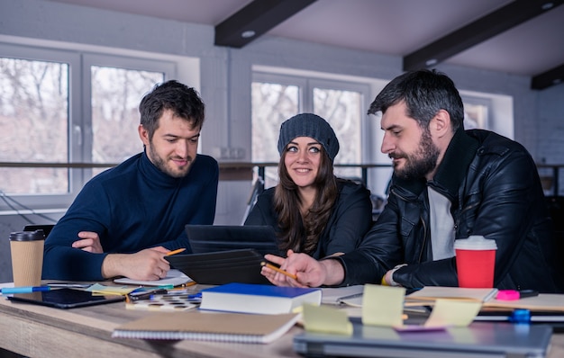 Equipo inteligente joven Grupo de gente moderna discutiendo el trabajo en tableta en la oficina