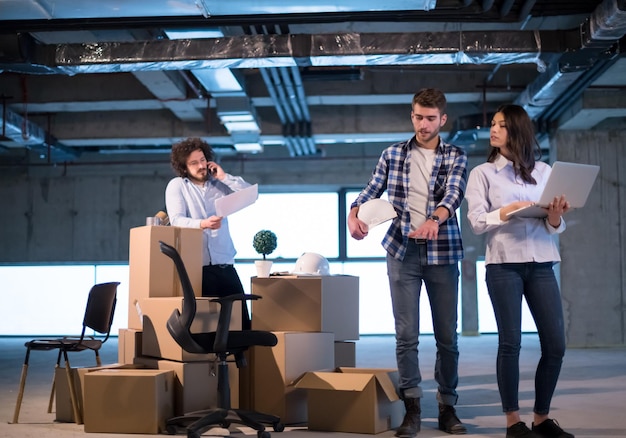 equipo joven de empresarios en grupo, arquitecto e ingeniero en el sitio de construcción revisando documentos y flujo de trabajo de negocios usando una computadora portátil en una nueva oficina de inicio