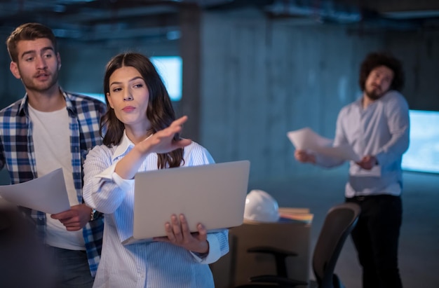 equipo joven de empresarios en grupo, arquitecto e ingeniero en el sitio de construcción revisando documentos y flujo de trabajo de negocios usando una computadora portátil en una nueva oficina de inicio